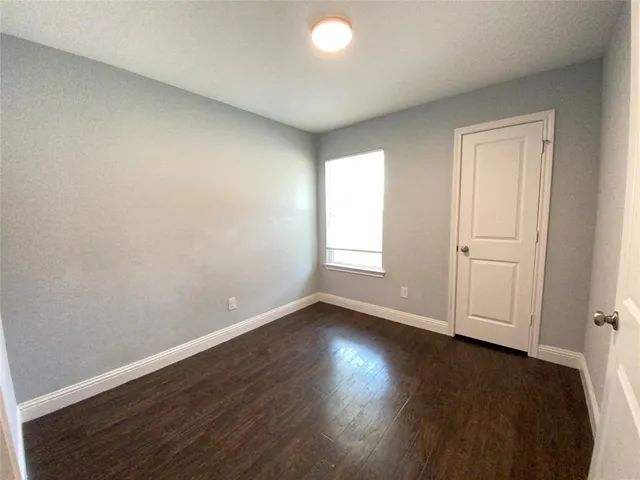 an empty room with wooden floor and window