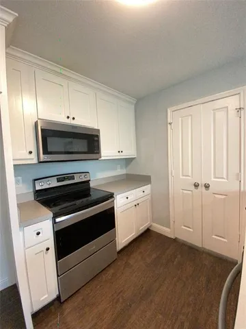 a kitchen with granite countertop a stove a sink and a microwave