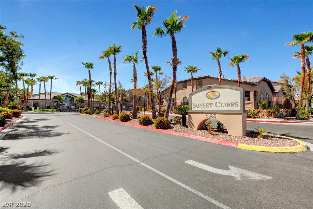 8985 South Durango Drive, Unit 2187 Las Vegas, NV 89113 - Photo 64 of 73 Enter a gated community defined by a bold sign, tropical palm trees, and well-maintained desert landscaping.