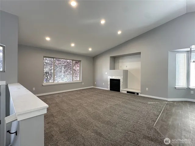 a view of an empty room with a fireplace and a window