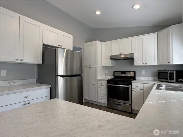 a kitchen with stainless steel appliances a refrigerator stove and white cabinets