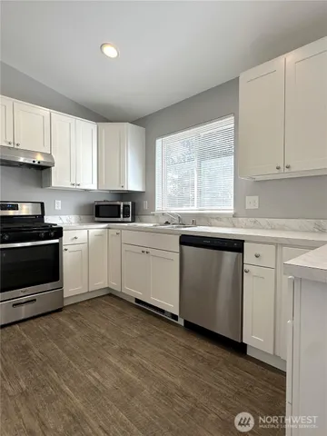 a kitchen with granite countertop white cabinets a sink and white appliances