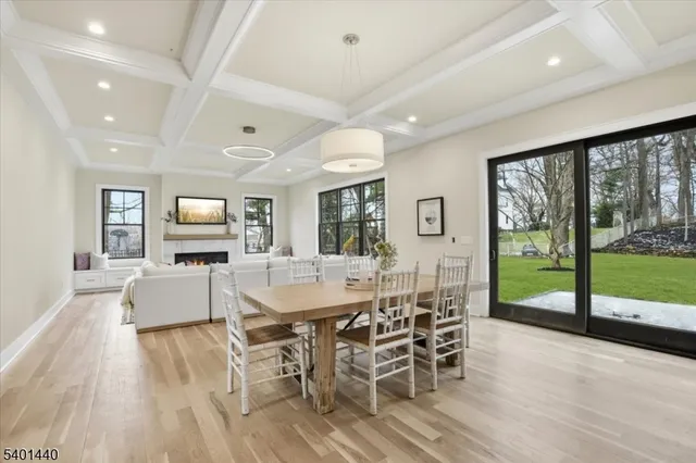 a dining room with wooden floor a chandelier a glass table and chairs