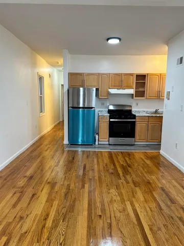 a large kitchen with stainless steel appliances wooden floors and a counter top space