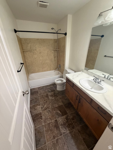 909 South Main Street, Unit F Layton, UT 84041 - Photo 11 of 20 Full bathroom featuring a single vanity with a white countertop and wood-finish cabinetry, a white toilet, and a bathtub with a tiled surround