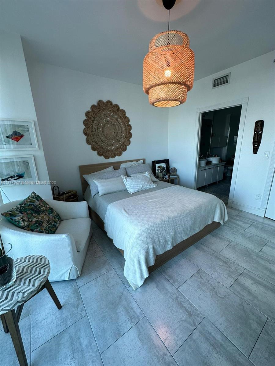 888 Biscayne Boulevard, Unit 3611 Miami, FL 33132 - Photo 4 of 13 a bedroom with a bed and a chandelier