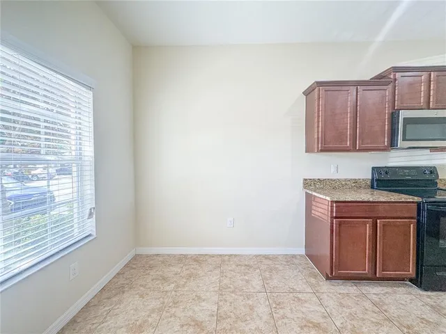 a kitchen with granite countertop a sink cabinets stainless steel appliances and a window