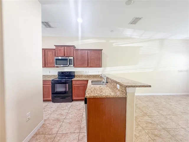 a kitchen with stainless steel appliances granite countertop a stove a sink and a microwave