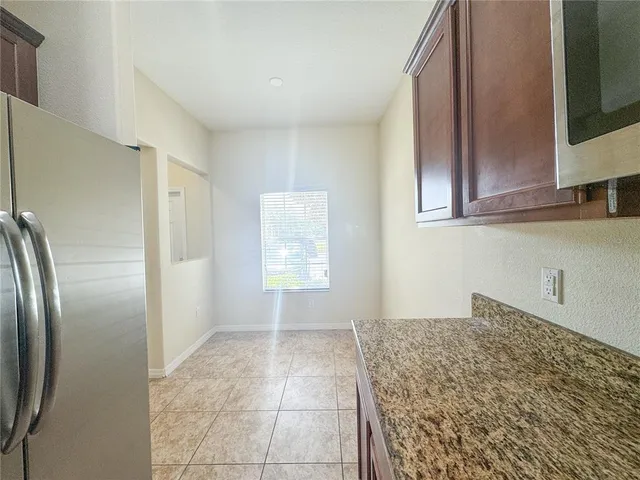 a kitchen with granite countertop a refrigerator and cabinets