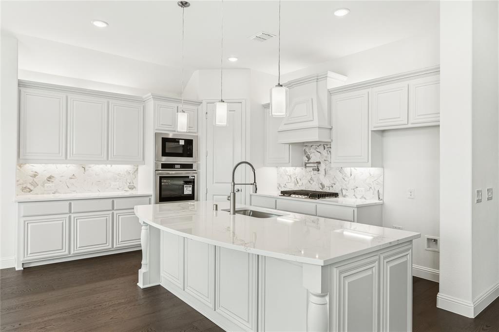 1145 Hitching Post Way Oak Point, TX 75068 - Photo 19 of 39 a kitchen with kitchen island granite countertop a sink a stove and cabinets