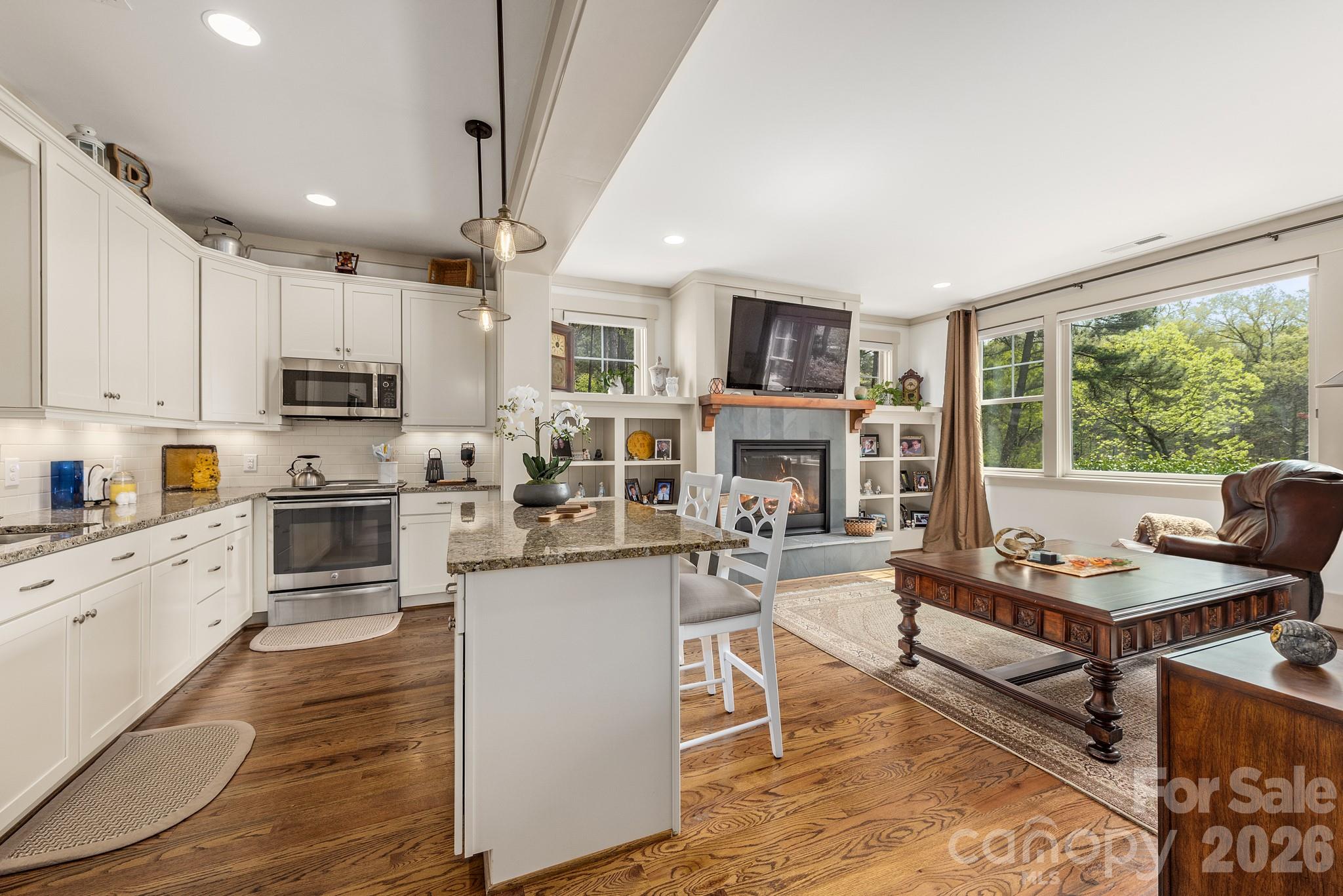 18321 Rosapenny Road Charlotte, NC 28278 - Photo 26 of 40 a kitchen with stainless steel appliances kitchen island granite countertop a stove top oven a sink dishwasher a dining table and chairs with wooden floor