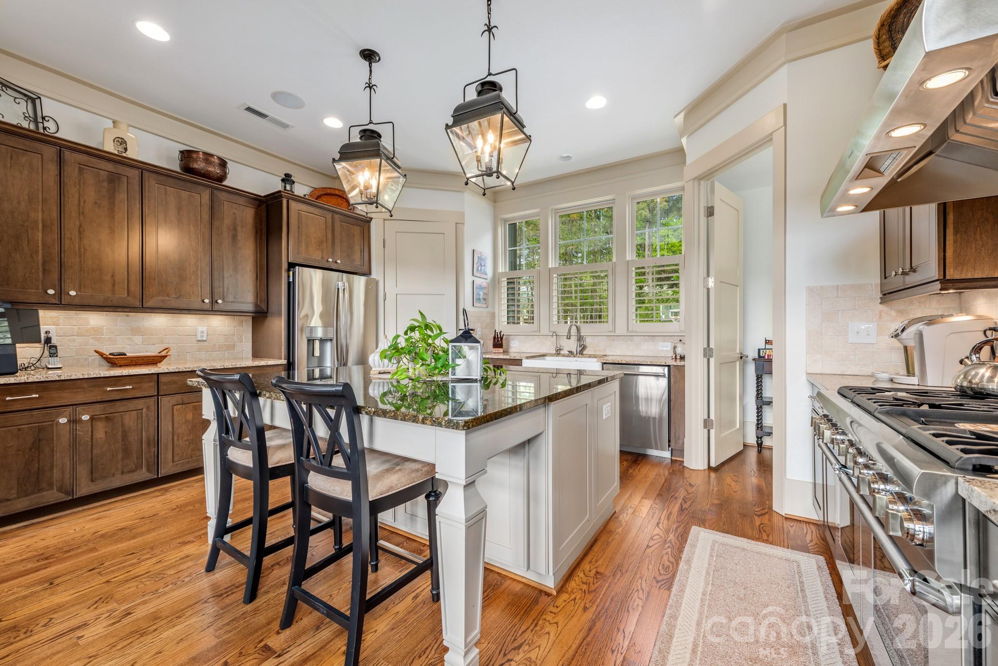 18321 Rosapenny Road Charlotte, NC 28278 - Photo 7 of 40 a kitchen with stainless steel appliances granite countertop a stove refrigerator a sink dishwasher a dining table and chairs with wooden floor