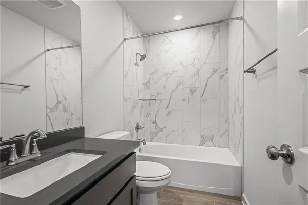 a bathroom with a granite countertop sink a toilet and shower