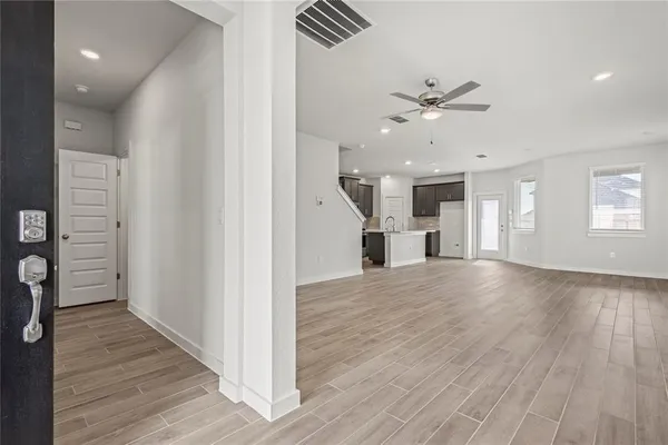 a view of an empty room with wooden floor and a ceiling fan