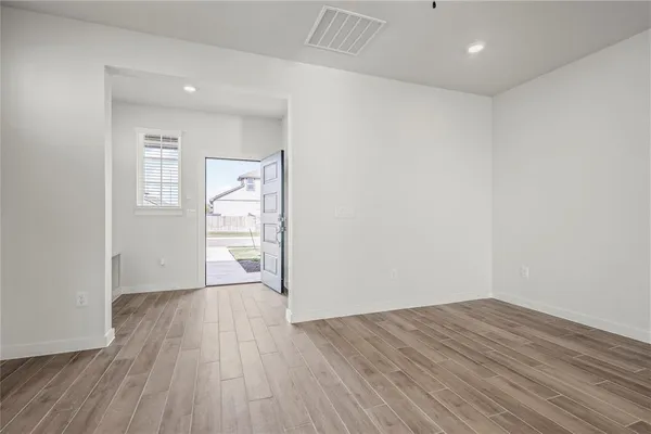 an empty room with wooden floor and windows