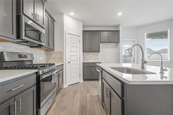 a kitchen with stainless steel appliances granite countertop a sink stove microwave and refrigerator