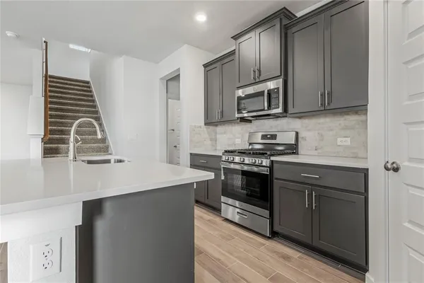 a kitchen with stainless steel appliances a stove microwave and sink