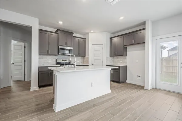 a kitchen with kitchen island granite countertop wooden floors white cabinets and stainless steel appliances