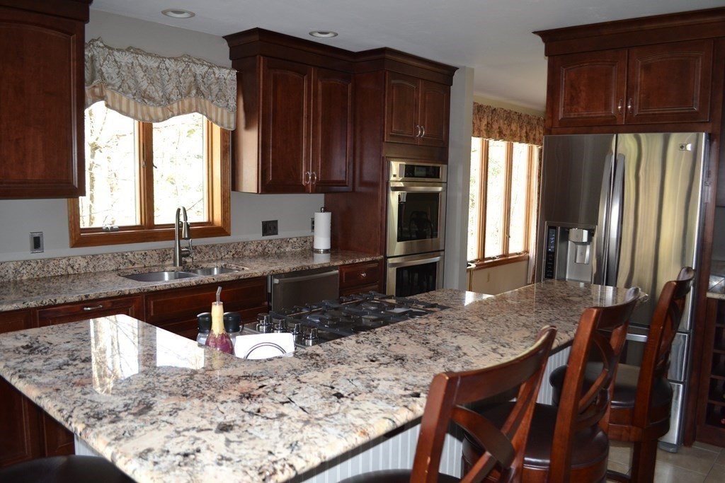 38 Lincoln Point Road Charlton, MA 01507 - Photo 8 of 25 a kitchen with granite countertop wooden cabinets refrigerator and microwave