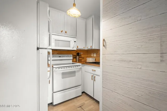 a kitchen with granite countertop white cabinets and white appliances