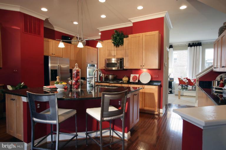 9839 Garden Ranges Laurel, MD 20723 - Photo 2 of 12 a kitchen with stainless steel appliances granite countertop a stove top oven a dining table and chairs with wooden floor