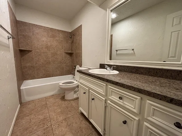 a spacious bathroom with a granite countertop sink a toilet and bathtub