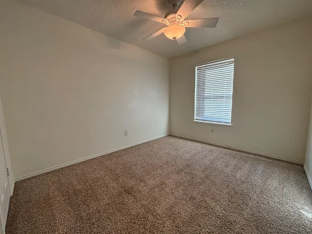 an empty room with a window and a fan