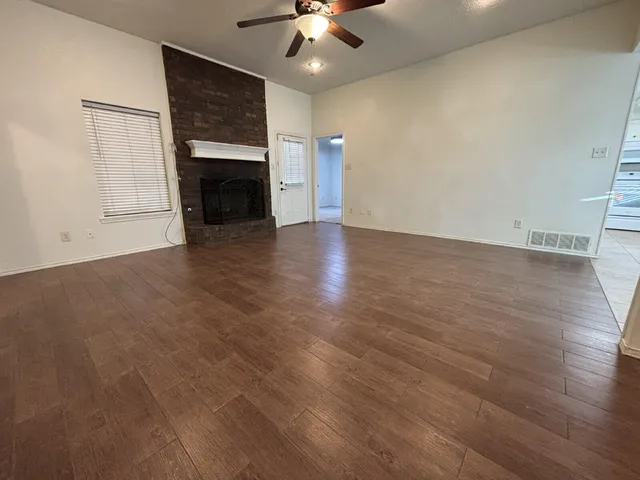 an empty room with wooden floor fireplace and fan