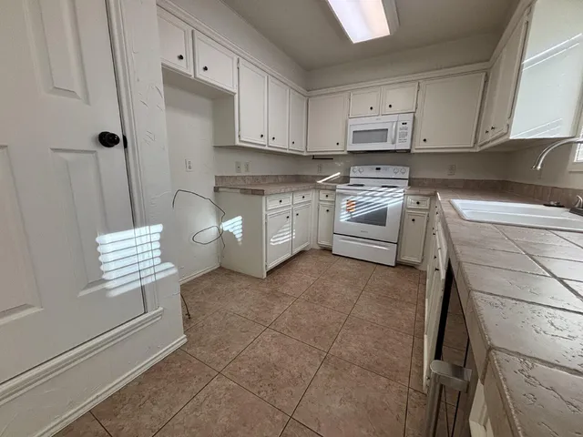 a kitchen with white cabinets and white appliances