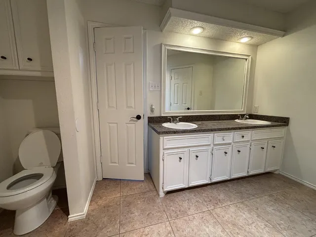 a spacious bathroom with a granite countertop toilet sink and mirror