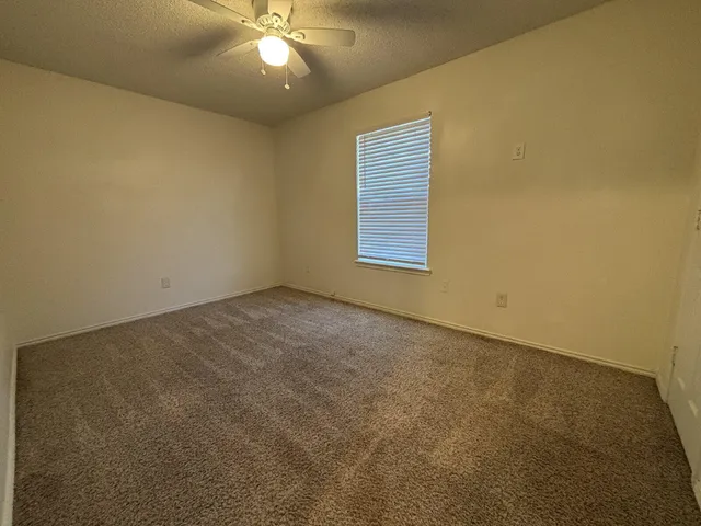 an empty room with a ceiling fan and window
