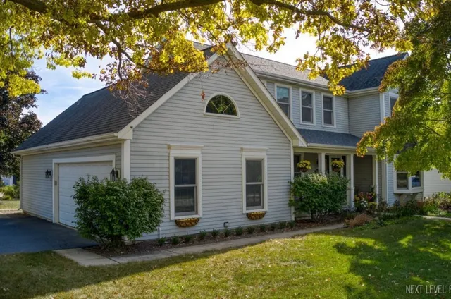 a view of a house with brick walls plants and large tree