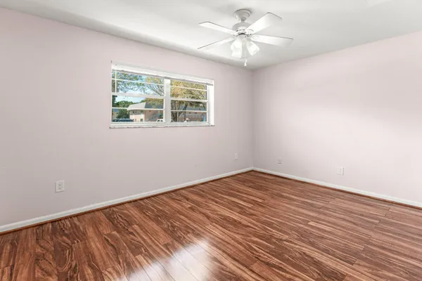 a view of empty room with wooden floor and fan