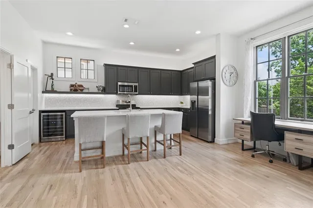 a kitchen with stainless steel appliances a dining table chairs refrigerator and sink