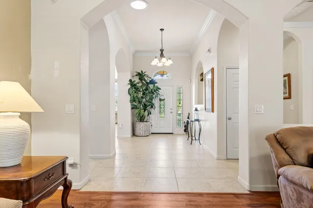 a dining room with furniture a chandelier and kitchen view