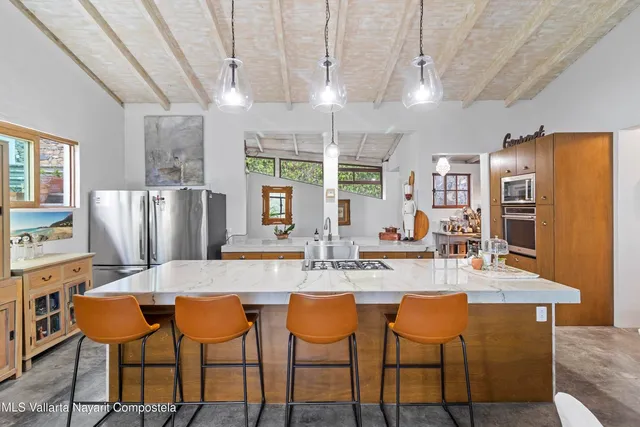 a kitchen with stainless steel appliances granite countertop a dining table chairs and granite counter tops