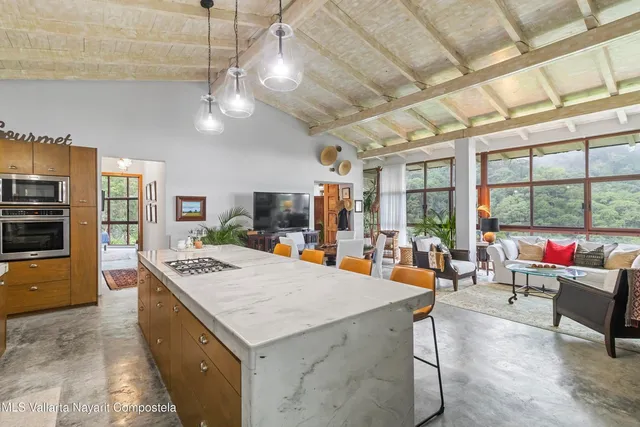 a large living room with stainless steel appliances kitchen island granite countertop lots of furniture and a chandelier