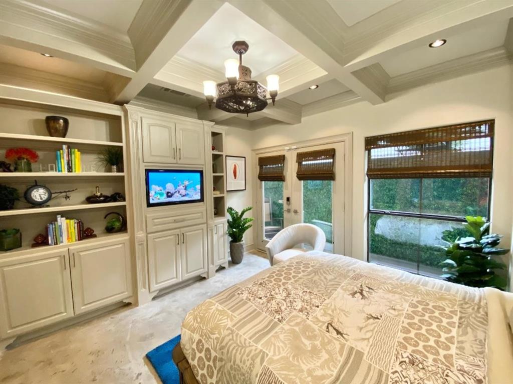 a large bedroom with furniture a flat screen tv and a large window