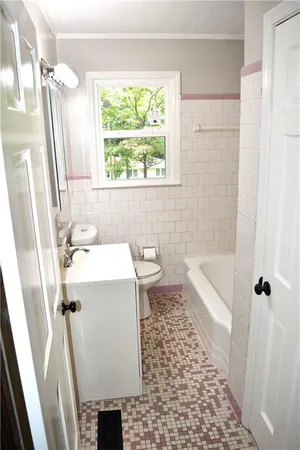 a bathroom with a sink a toilet a window and shower