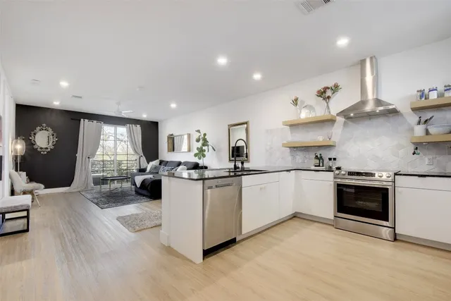 a kitchen with stainless steel appliances granite countertop a stove a sink a refrigerator and white cabinets