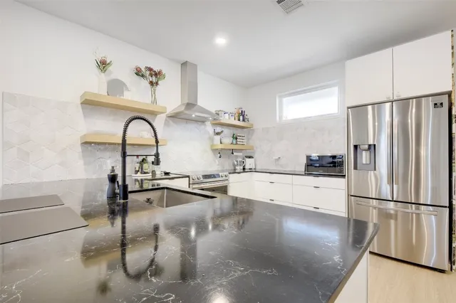 a kitchen with stainless steel appliances granite countertop a refrigerator a stove and a sink with wooden floor