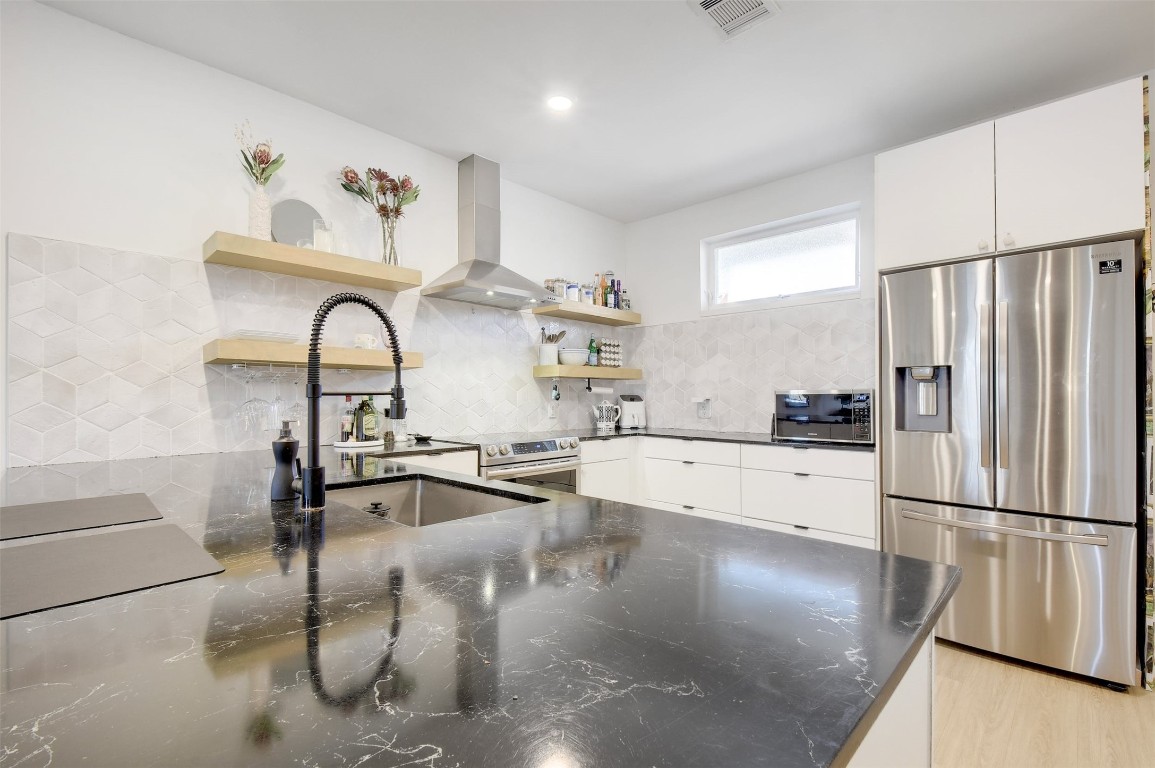 2709 East 5th Street, Unit 2303 Austin, TX 78702 - Photo 5 of 18 a kitchen with stainless steel appliances granite countertop a refrigerator a stove and a sink with wooden floor