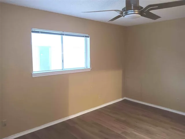 an empty room with wooden floor closet and windows