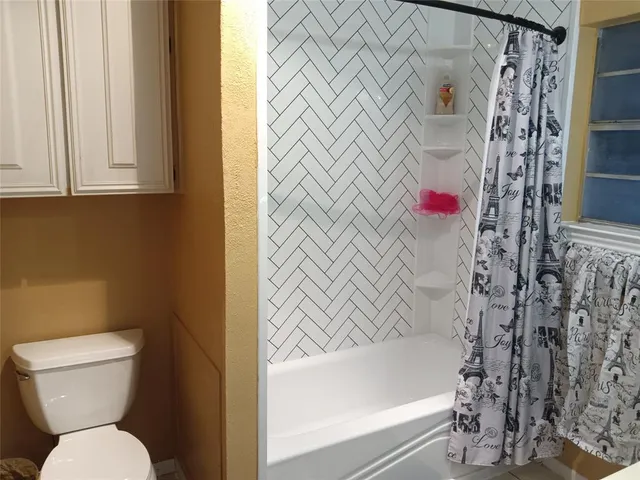 a bathroom with a toilet and a shower curtain