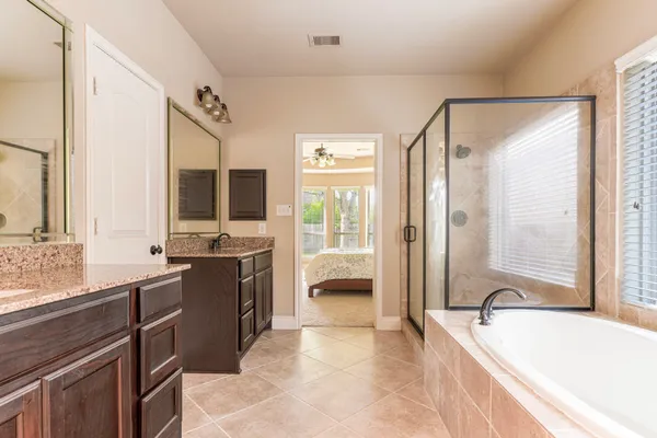 a spacious bathroom with a granite countertop tub sink a mirror a vanity and a shower