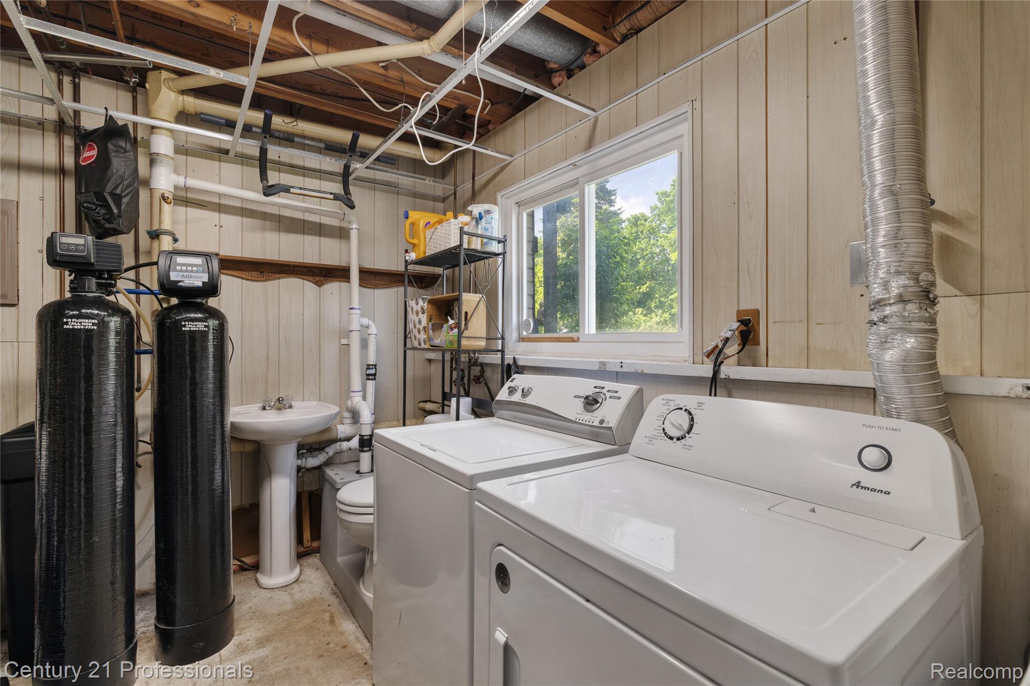 15037 Hogan Road Linden, MI 48451 - Photo 27 of 38 Laundry area featuring a window, paneled walls, exposed ceiling joists, pedestal sink, and water filtration system