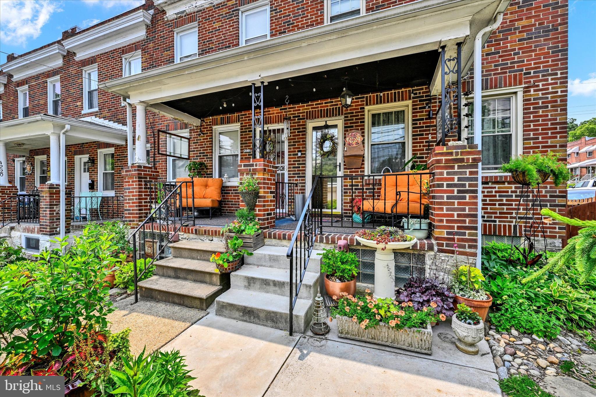 a view of a house with potted plants and a bench