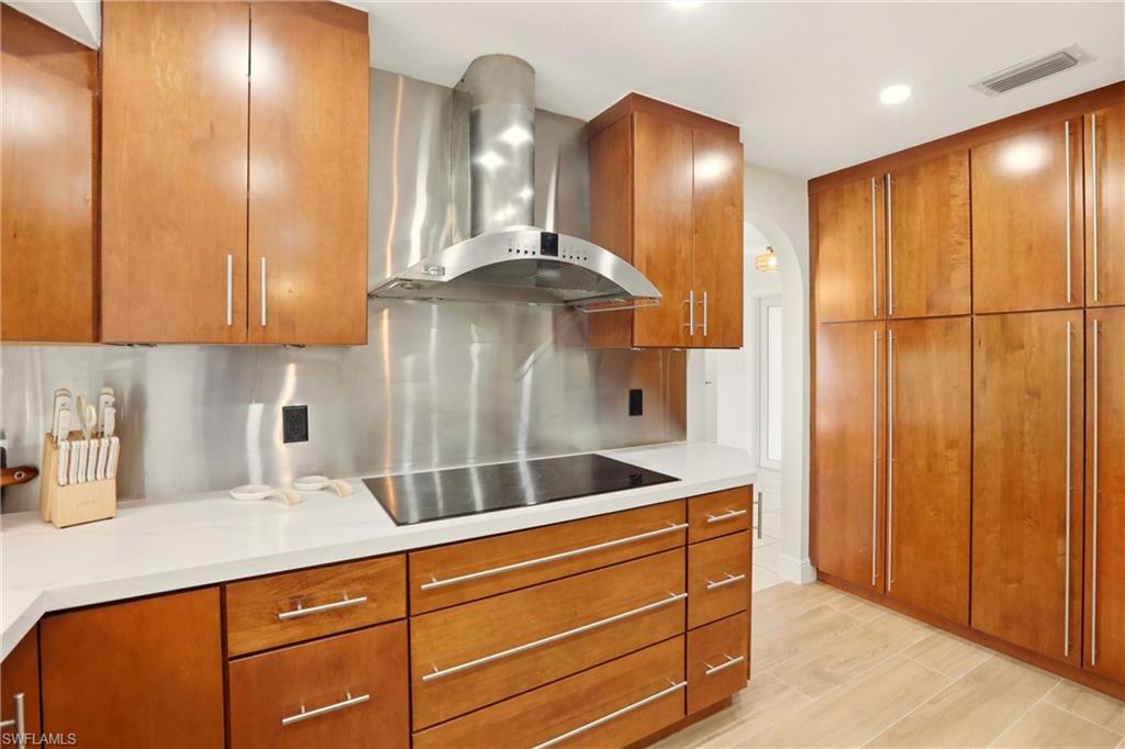 339 Landmark Street Marco Island, FL 34145 - Photo 12 of 50 Kitchen with wall chimney range hood and brown cabinetry