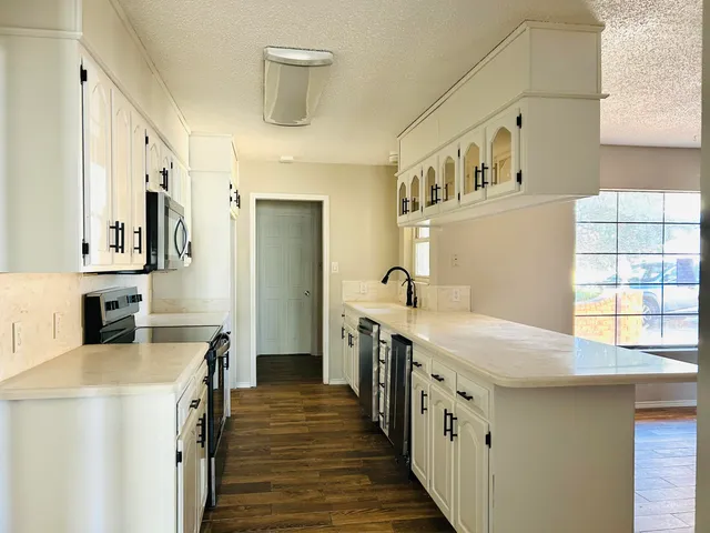 a kitchen with stainless steel appliances a sink a stove and wooden floor