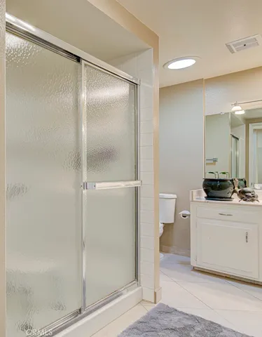 a bedroom that has a bed and a lamp on the dresser